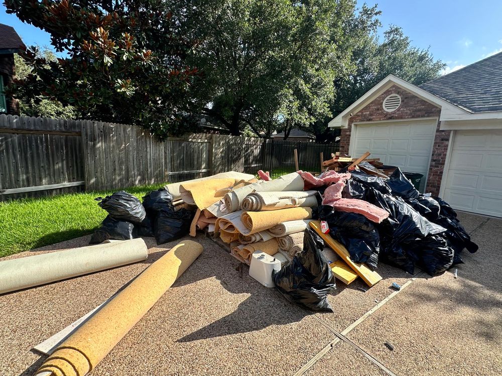 Before: old carpet, padding, and debris piled in driveway